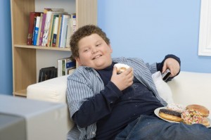 picture of overweight boy eating junk food and watching television