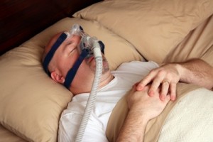 Caucasian man with sleep apnea using a CPAP machine in bed
