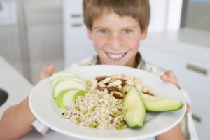 picture of Young boy in kitchen eating rice fruit and nuts smiling