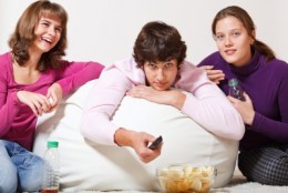 picture of Three cheerful teens watching TV and laughing