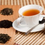 picture of cup of  tea near three piles of various kinds of tea