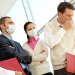 picture of Group of associates in protective masks looking strictly at coughing man